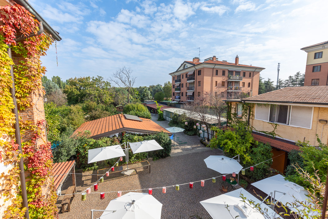 Vista dall'alto del cortile e degli edifici bassi circondati da alberi e verde.